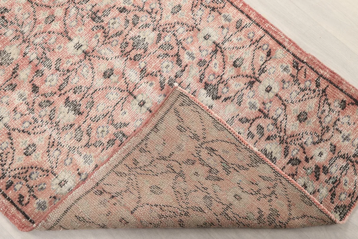 Corner of the rug folded back to reveal the cotton foundation and the reverse side of the hand-knotted pile.