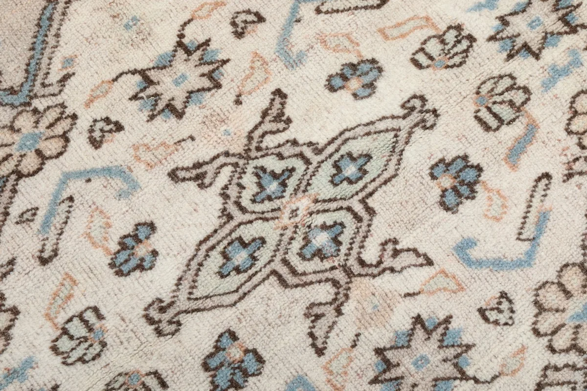 Macro detail of the hand-knotted wool pile, showing individual motifs and color variations in blue, brown, and ivory