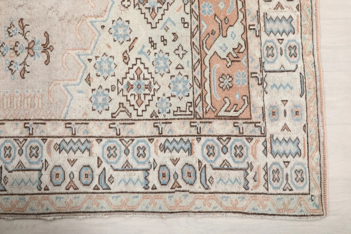 Detail of the rug's outer border design featuring geometric shapes and a rust-colored inner border section