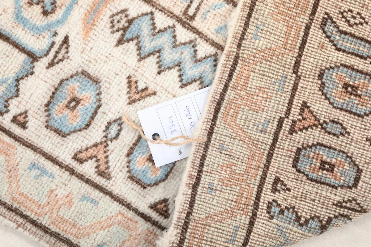 Detail of the low wool pile and the hand-knotted construction, with a tag visible