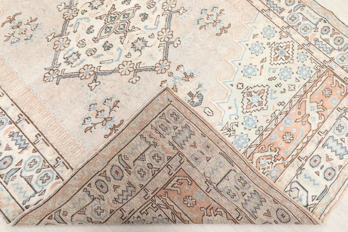 Corner of the rug folded back to reveal the back of the hand-knotted cotton foundation