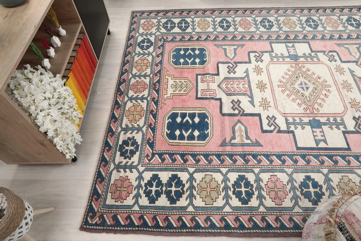 Wide angle view of the vintage rug in a room, showing its full design and colors