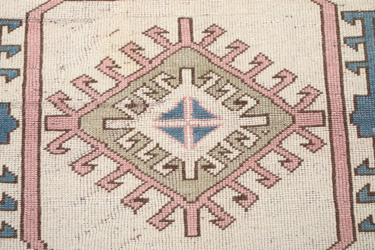 Close-up of the central medallion with intricate geometric patterns in cream, pink, and olive