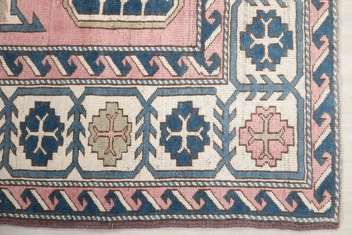 Detail of the rug's navy and cream geometric border design with pink accents