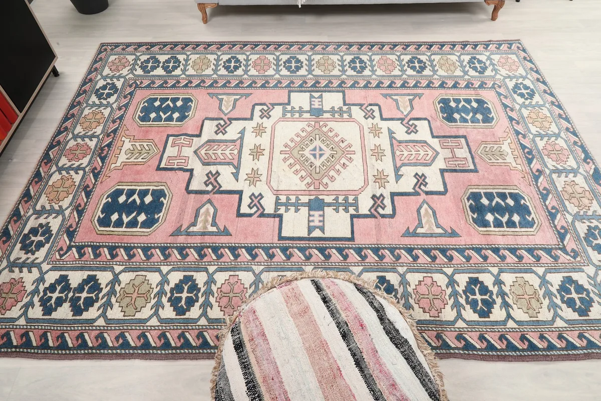 Full overhead view of the vintage pink and navy rug in a room with a decorative ottoman