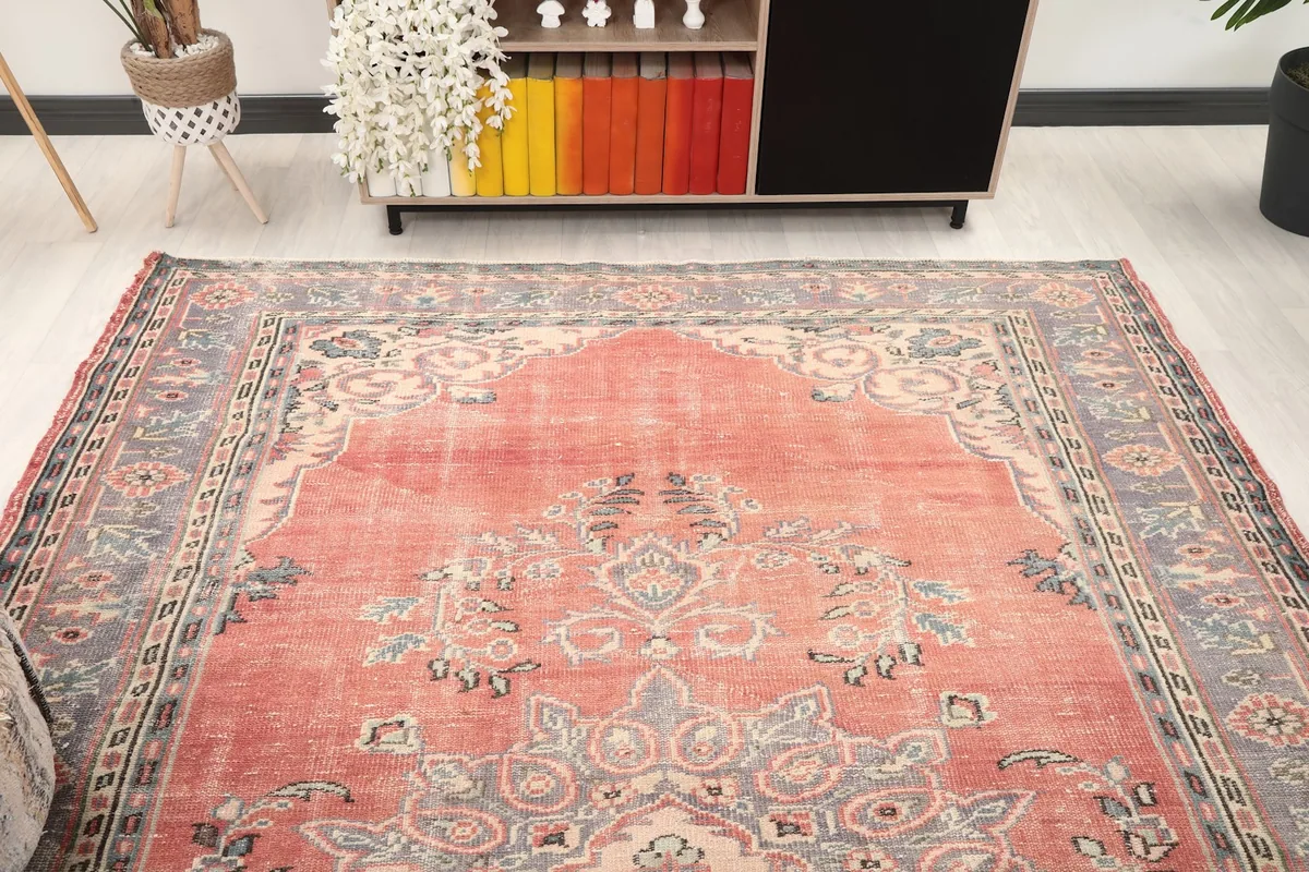 Overhead view of the vintage rug in a room setting, highlighting its overall pattern and colors.
