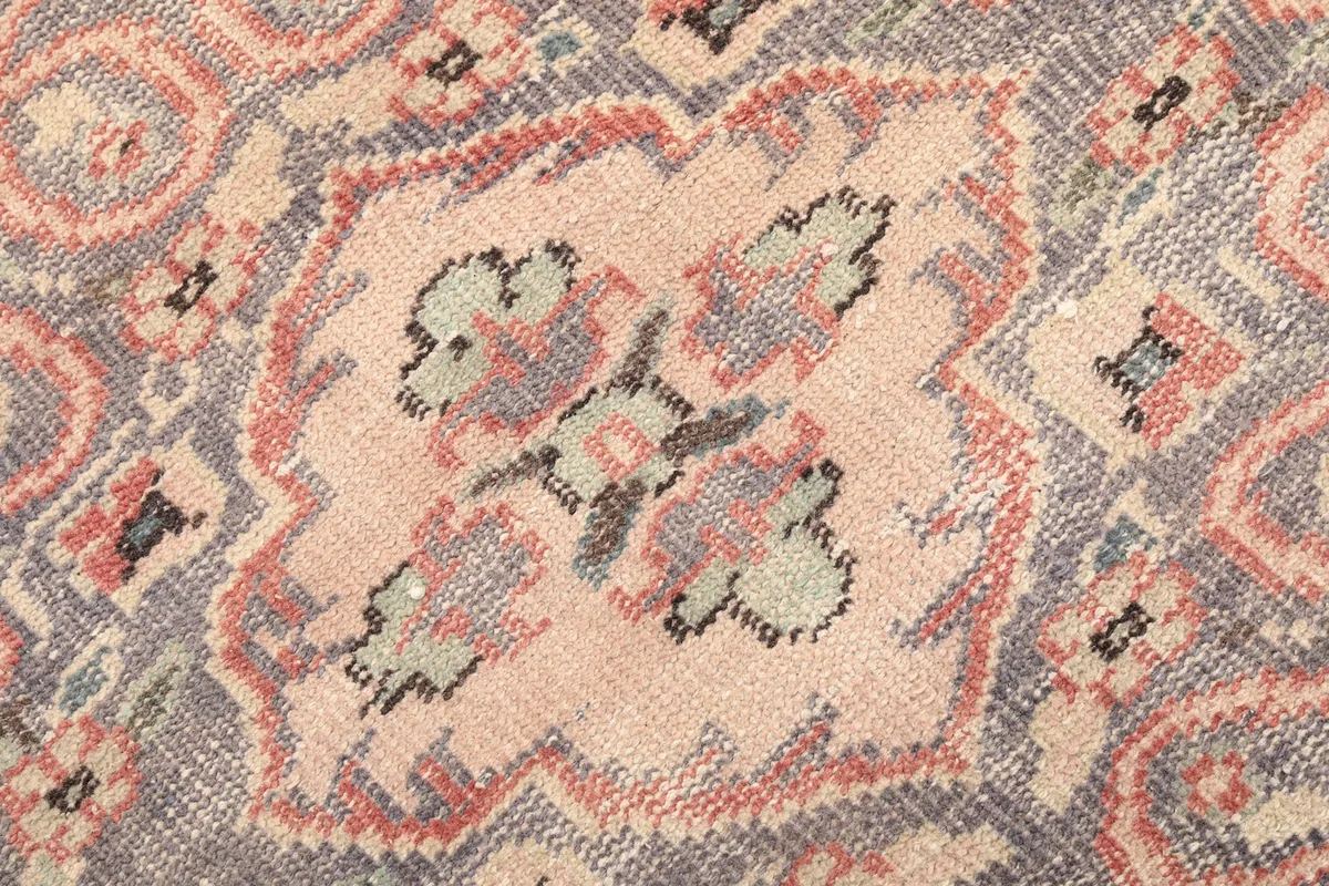 Close-up of the distressed texture and color variations within the rug's central design.
