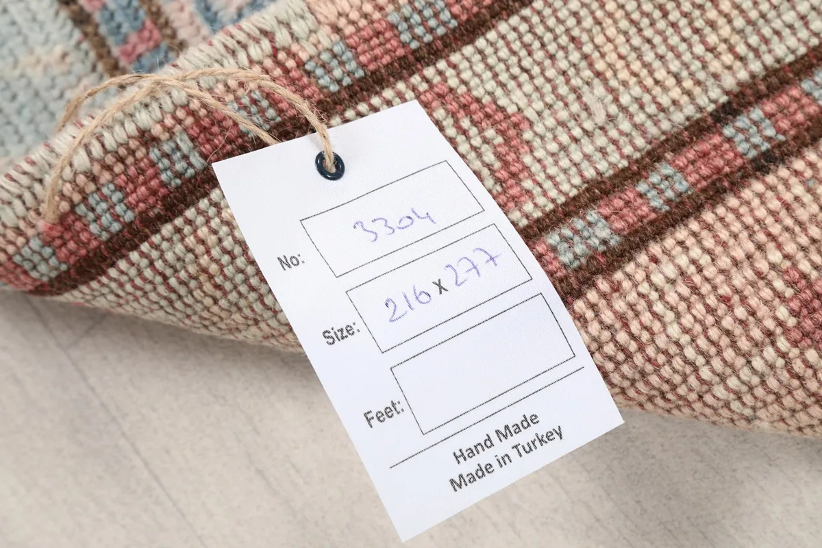 Product tag on the rug showing details like size and origin, indicating handmade quality