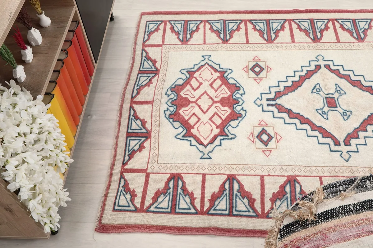 View of the rug's surface and patterns, with a corner of a striped pouf in the foreground.