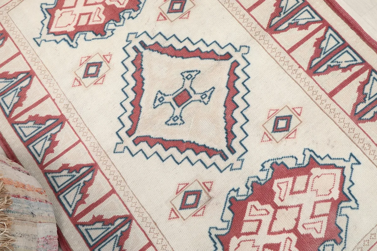 Close-up of a central geometric motif in red and blue, showing the wool pile texture.