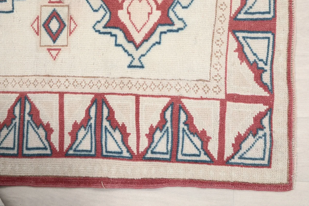 Detail view of the rug's red and blue geometric border pattern in one corner.