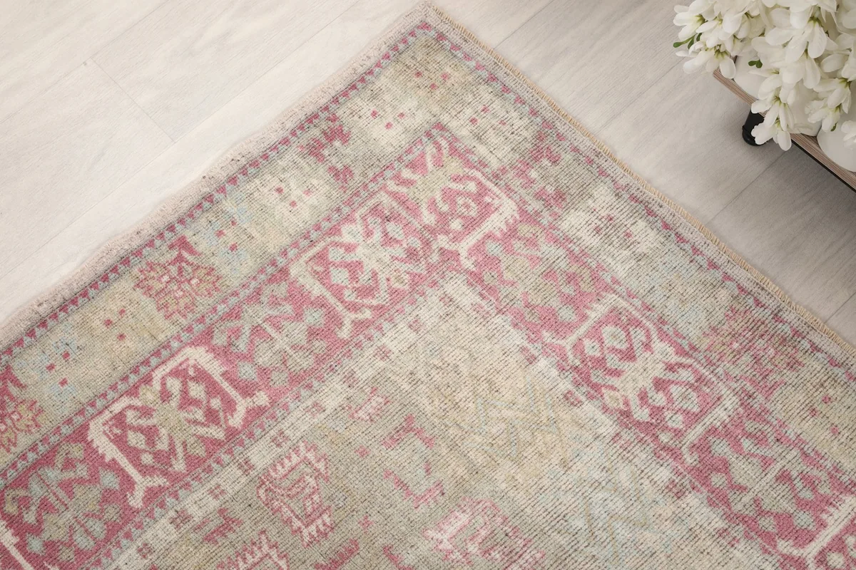 Close-up of the rug's rose border with intricate tribal patterns and natural wear