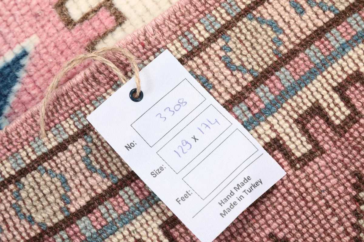 Product tag on the rug displaying the size (129 x 174 cm) and hand-made origin