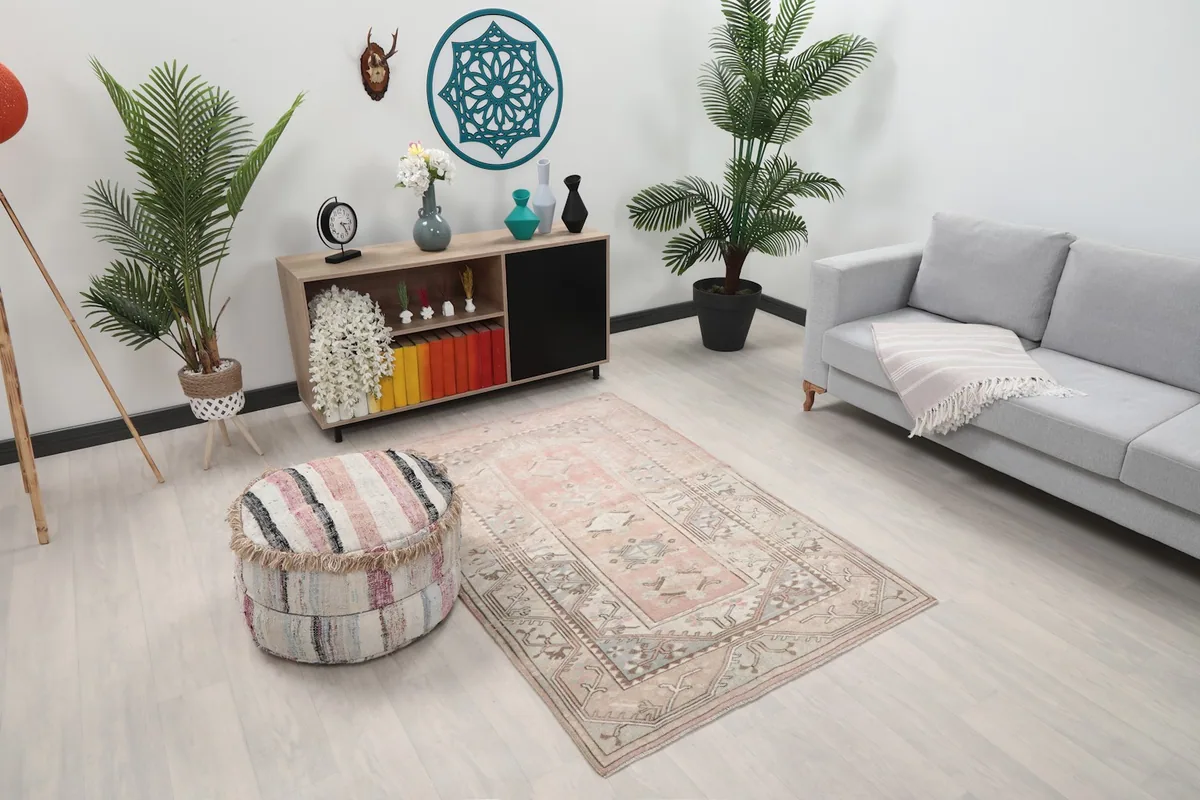 Angle view of the rose and beige geometric rug in a living space with a sofa and plants