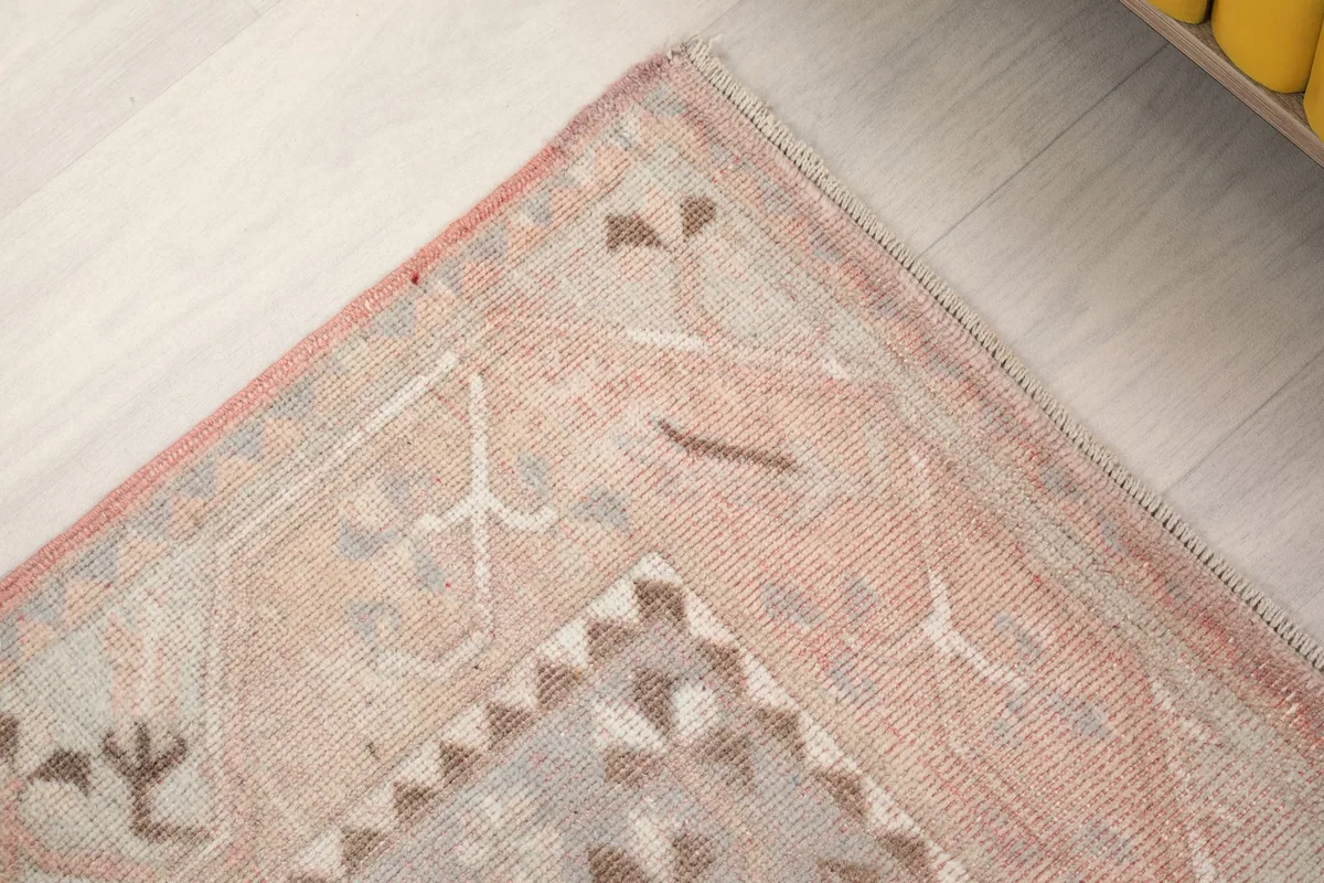 Close-up of a corner, revealing the intricate border and subtle color shifts in the vintage rug