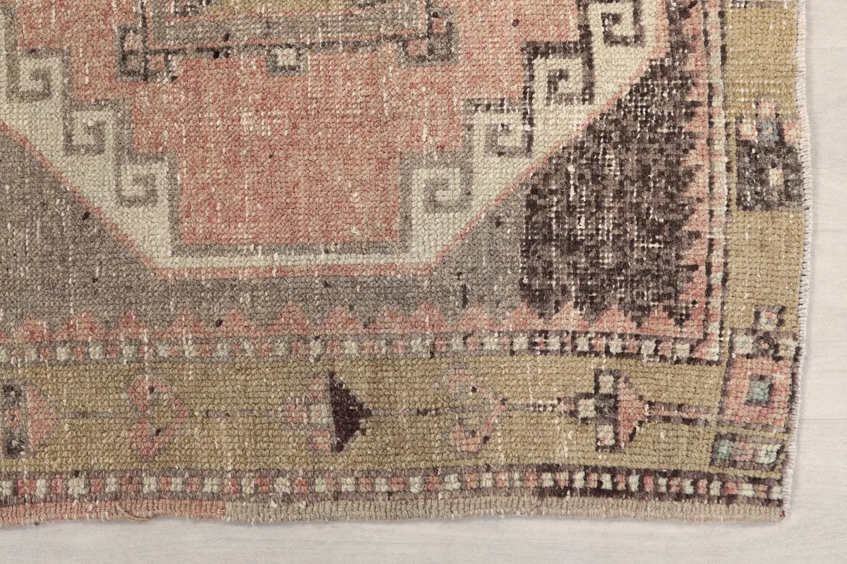 Detailed view of the corner of the runner, showing the beige and olive border pattern and edge