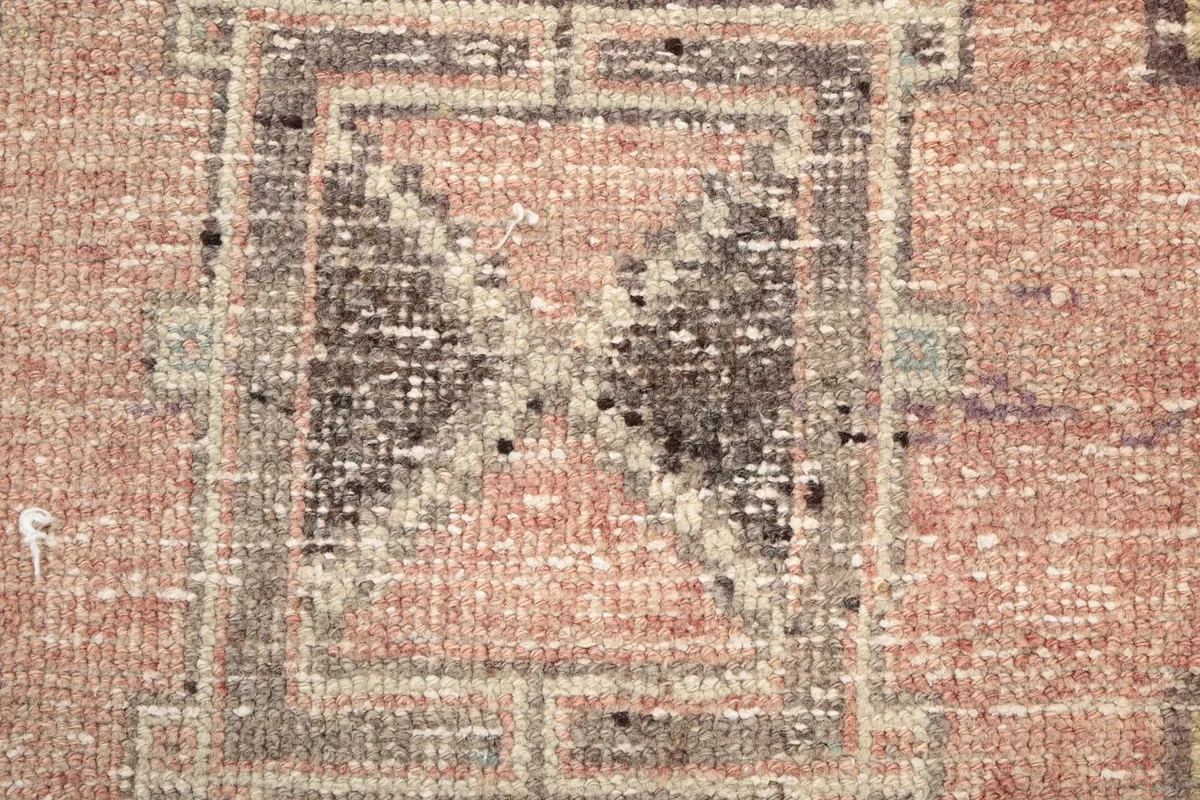 Texture of the hand-knotted wool pile, highlighting the low pile height and vintage wear