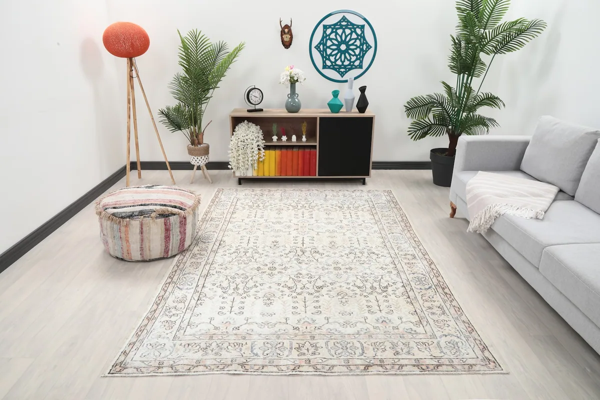 Ivory vintage area rug displayed in a modern living room setting with a sofa and pouf