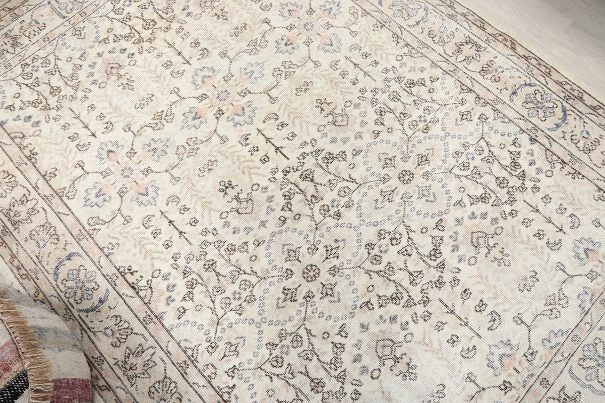 Overhead view of a section of the ivory rug, focusing on the central medallion and field patterns