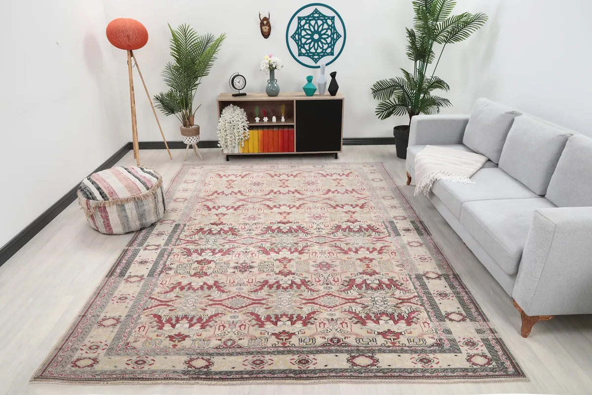 Vintage Anatolian rug in a living room setting, showing its scale with a sofa and ottoman