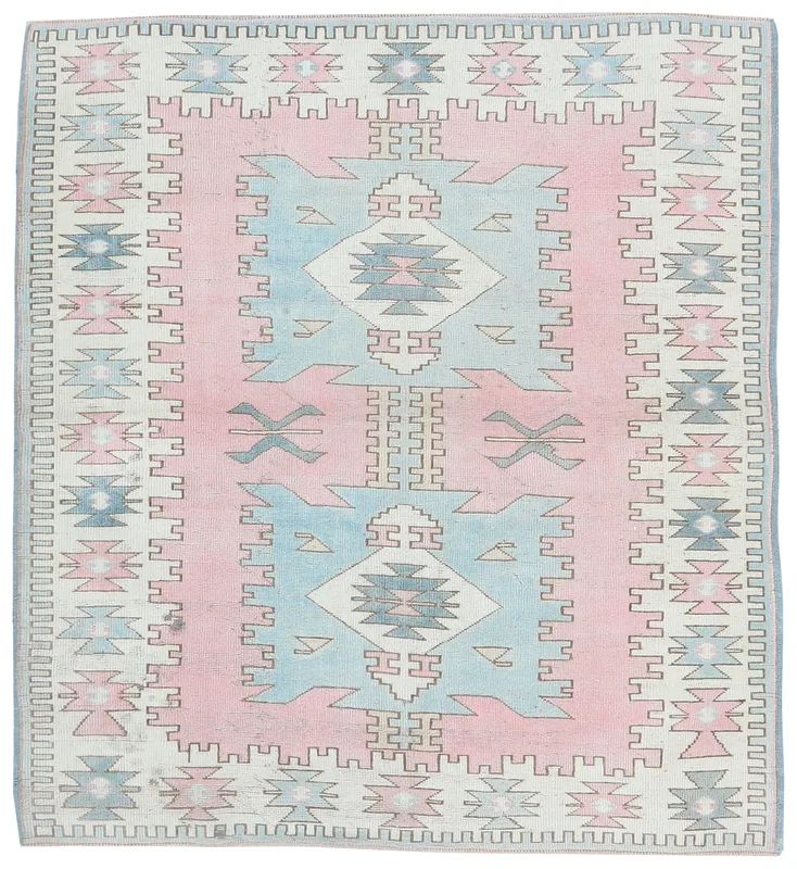 Full overhead view of the vintage pink, blue, and ivory geometric Anatolian rug