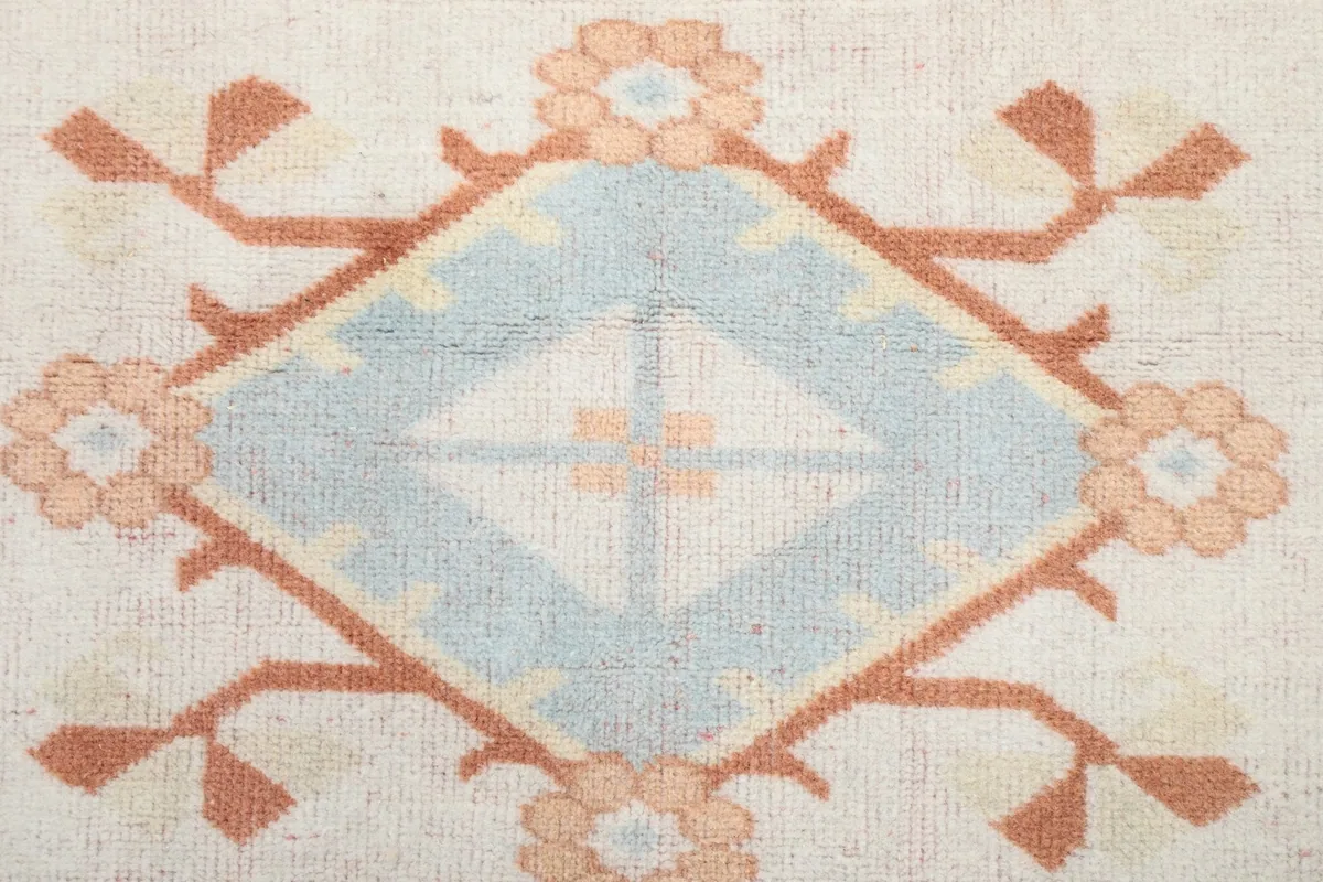 Macro close-up of a blue and orange geometric diamond motif in the rug's center