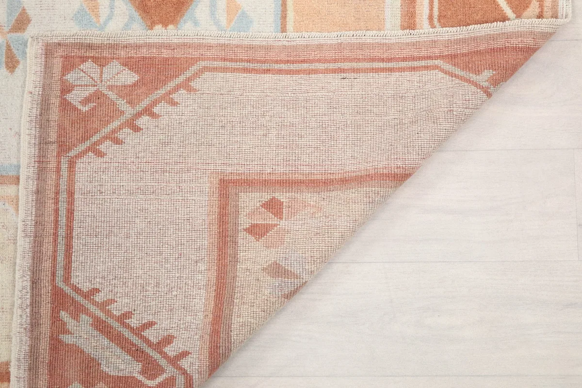 Underside of the rug shown by a folded corner, displaying the hand-knotted cotton foundation