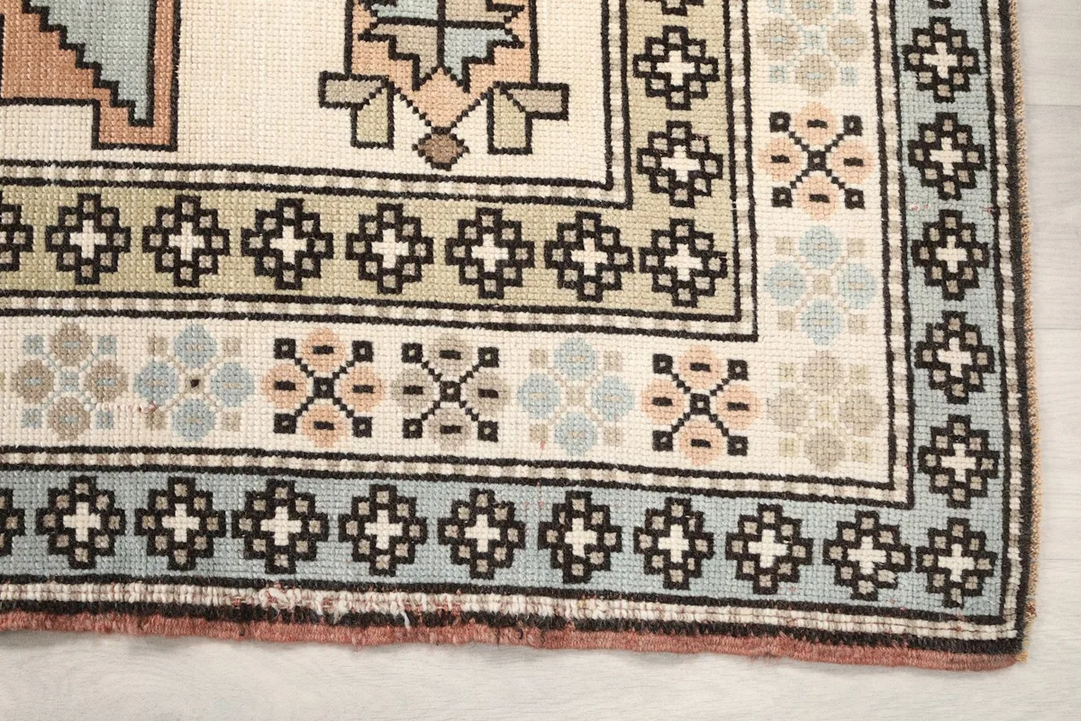 Detailed view of the rug's border and corner motifs, showing blue and green elements