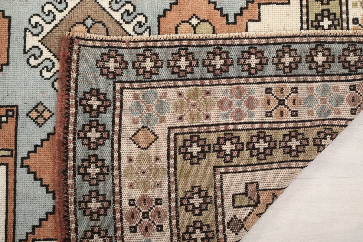 Close-up of the rug's pile and knotting, with a folded corner showing the reverse