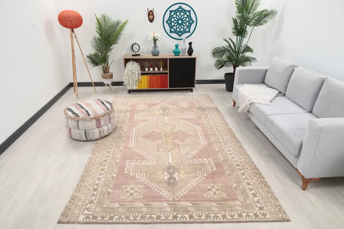 Rose toned geometric rug displayed in a living room setting with a light gray couch