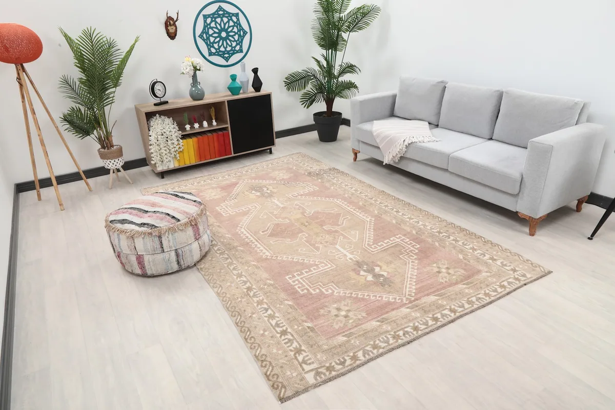 Angle view of the rose toned rug in a room, showing its placement relative to furniture