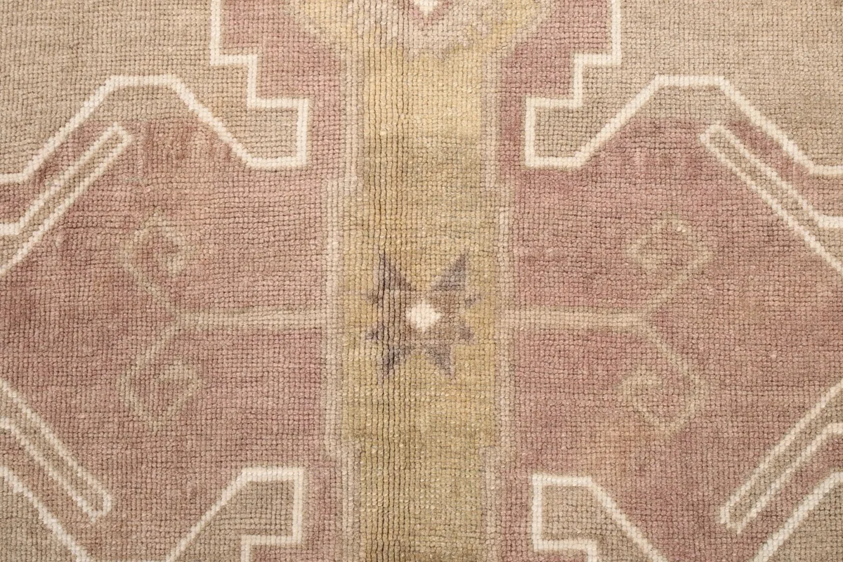 High-resolution close-up of the rug's rose and gold toned wool pile texture and knotting