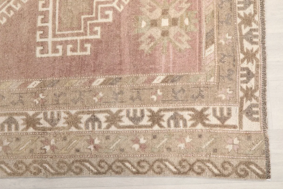 Detailed view of the intricate geometric patterns in the beige and tan border of the rug