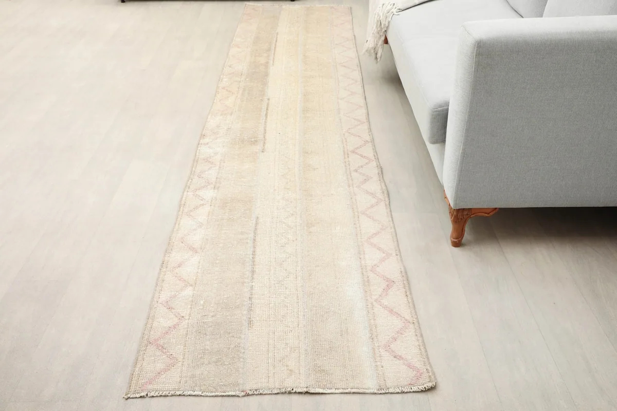 Vintage Anatolian runner rug laid out in a room, showing its length next to a sofa