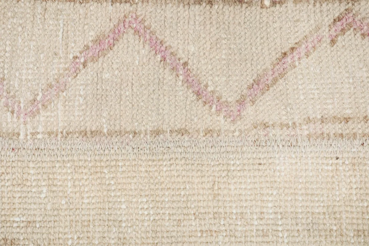 Extreme close-up of the rose geometric motif and the intricate weaving of the wool pile