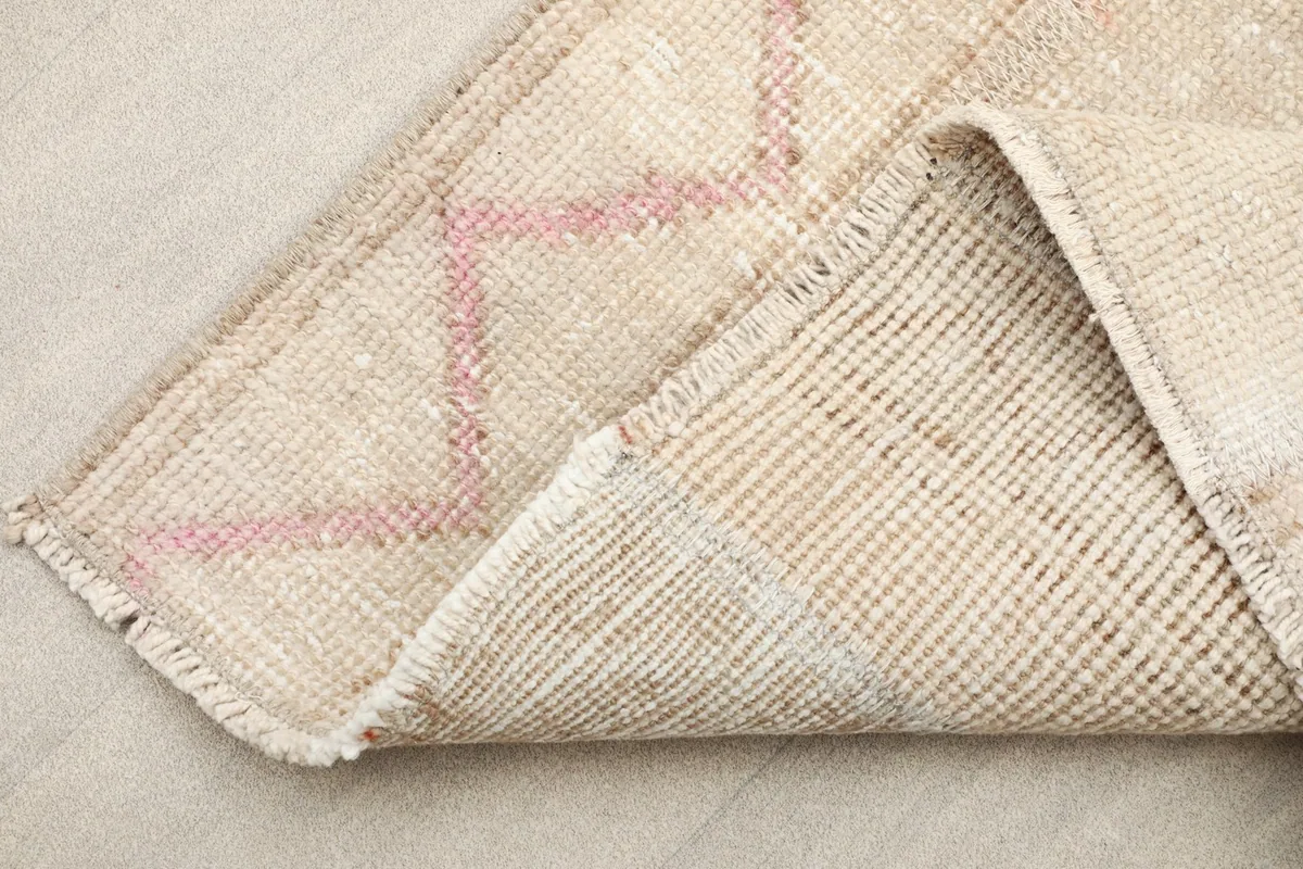 Corner of the rug folded to show the cotton foundation and the reverse side of the hand-knotting