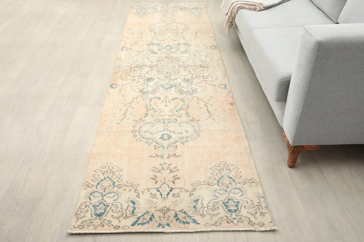 Runner rug laid out in a modern living space next to a light gray sofa, showing its length and colors.