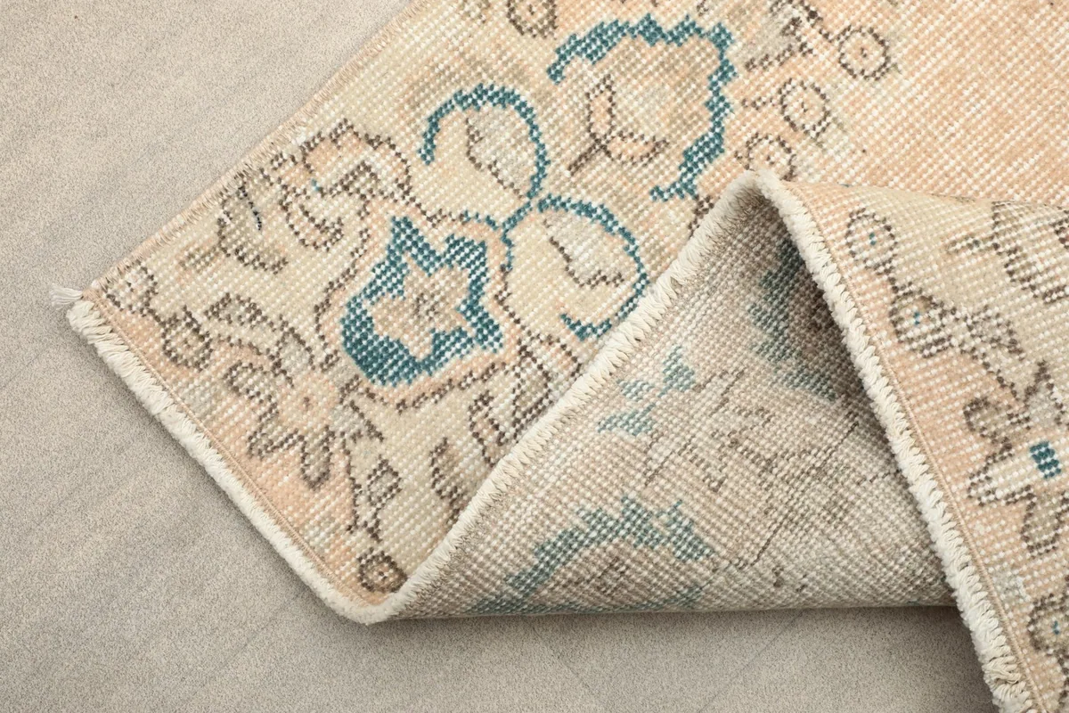 Folded corner of the rug, revealing the reverse side and the cotton foundation.