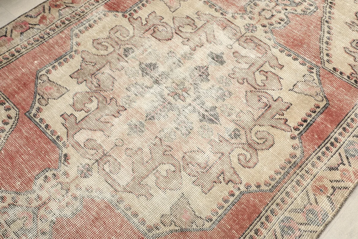 Detailed view of the central medallion, showing the faded rust and beige tones and intricate patterns