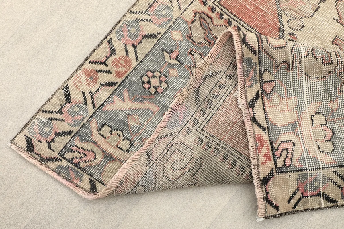 Folded corner of the rug, displaying the back of the hand-knotted cotton foundation and pile thickness
