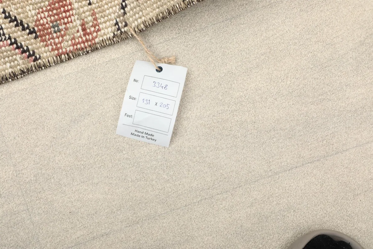 Tag attached to the rug, indicating its size in centimeters and origin as hand-made in Turkey