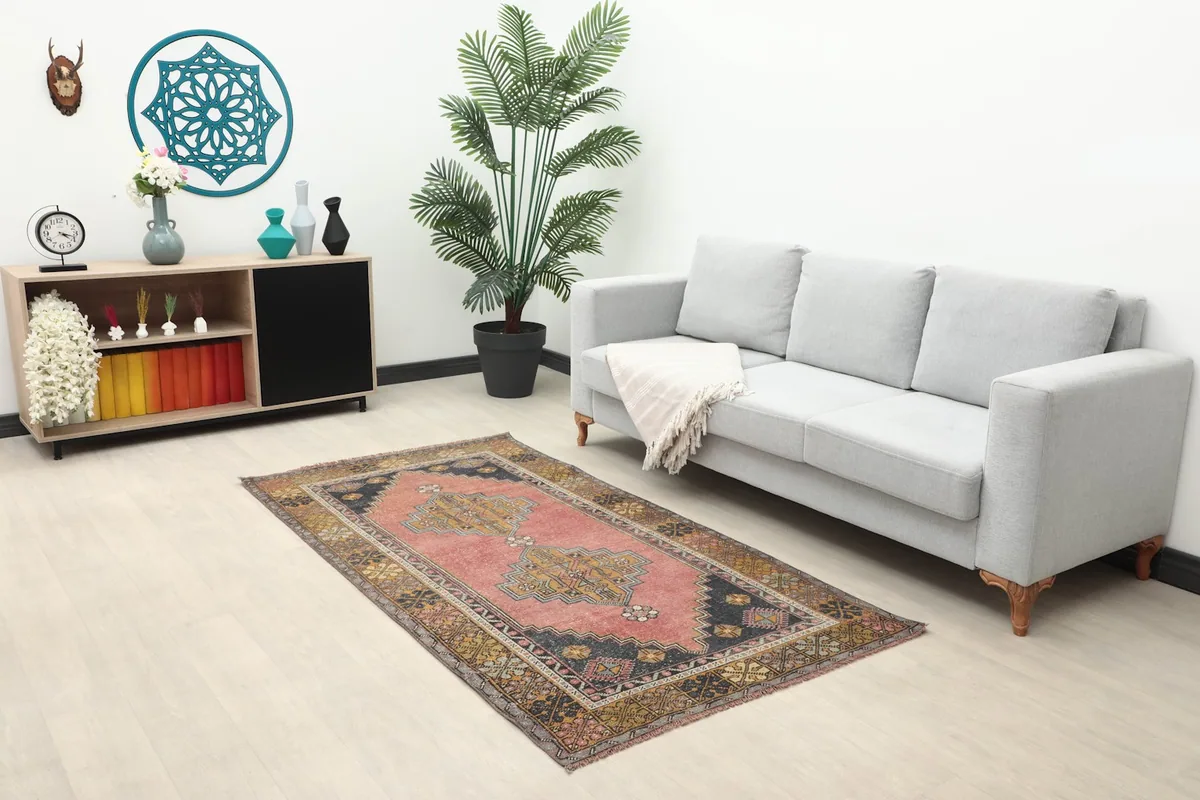 Small rose area rug placed in a living room scene with a sofa and decor
