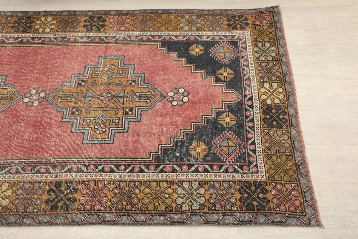 Close-up detail of the rug's rose field, black corner motifs, and border patterns