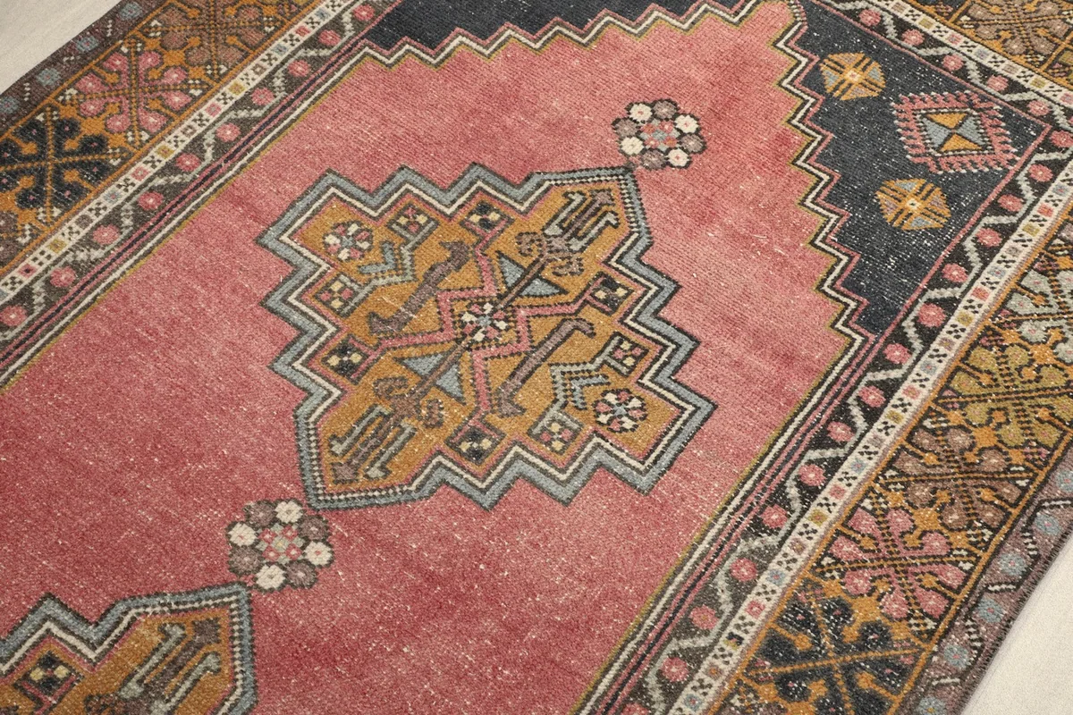 Detailed view of the central gold and blue geometric medallion on the rose field