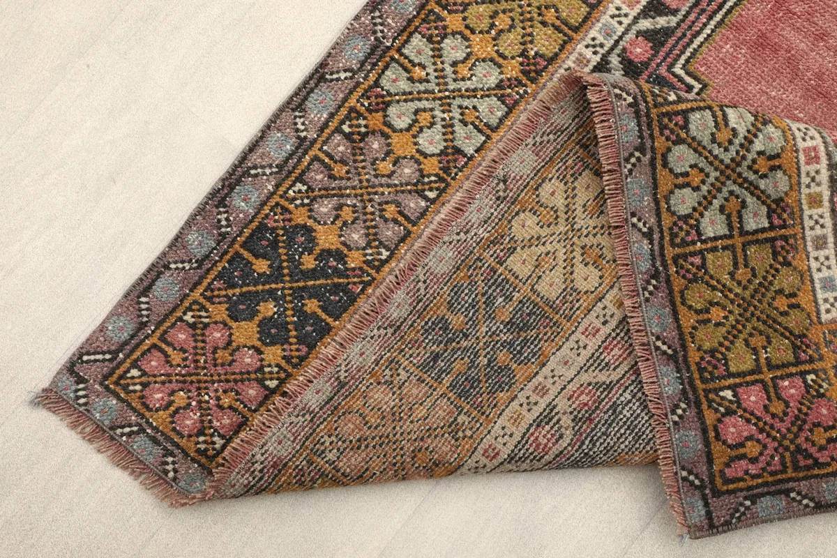 Folded corner of the rug revealing the reverse side and the hand-knotted cotton foundation