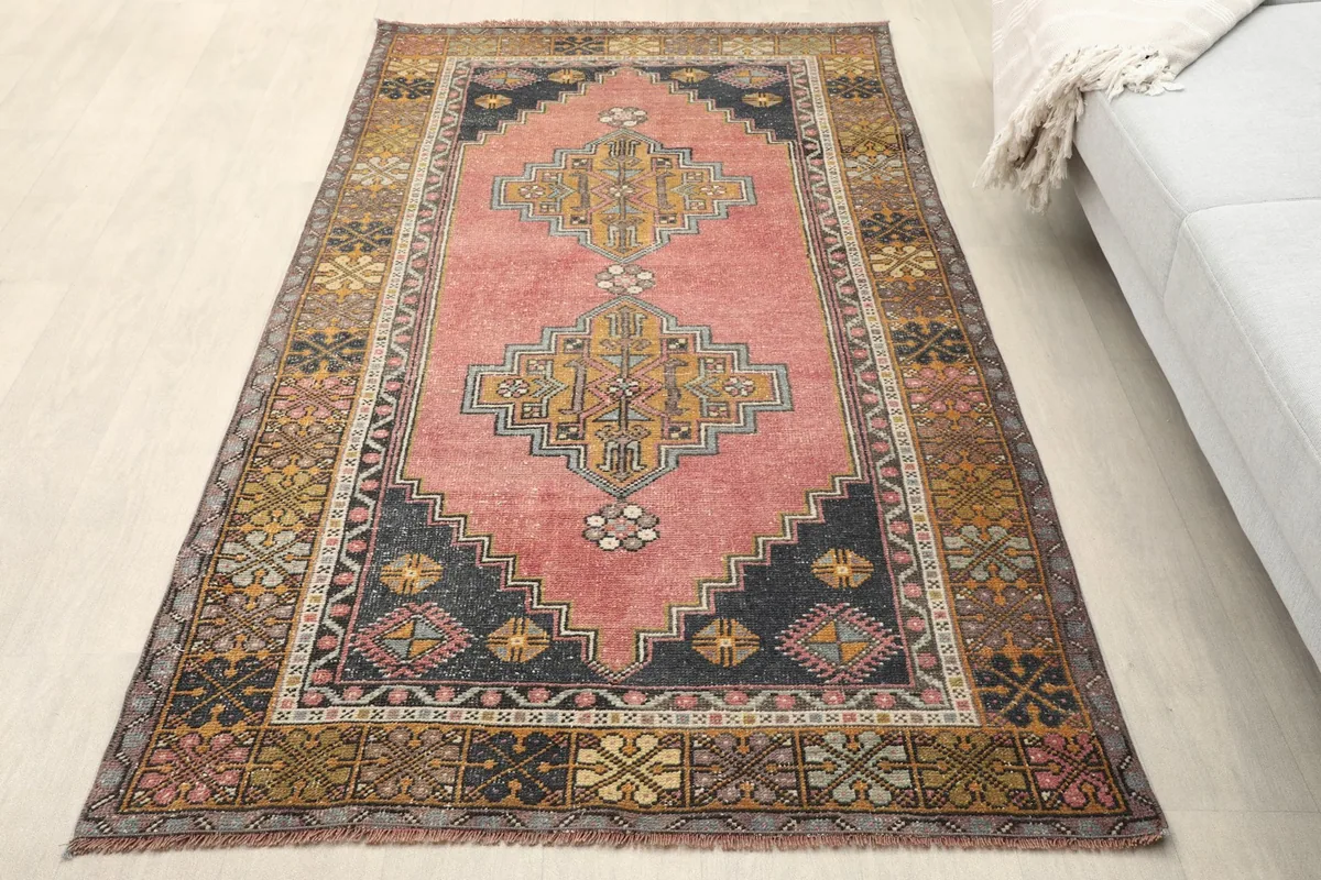 Overhead view of the rose tribal rug in a room setting, showing its colors and pattern