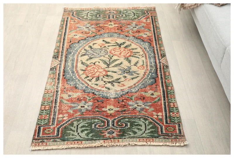 Full top view of the rust, green, and blue vintage Anatolian rug with a floral medallion on a white background