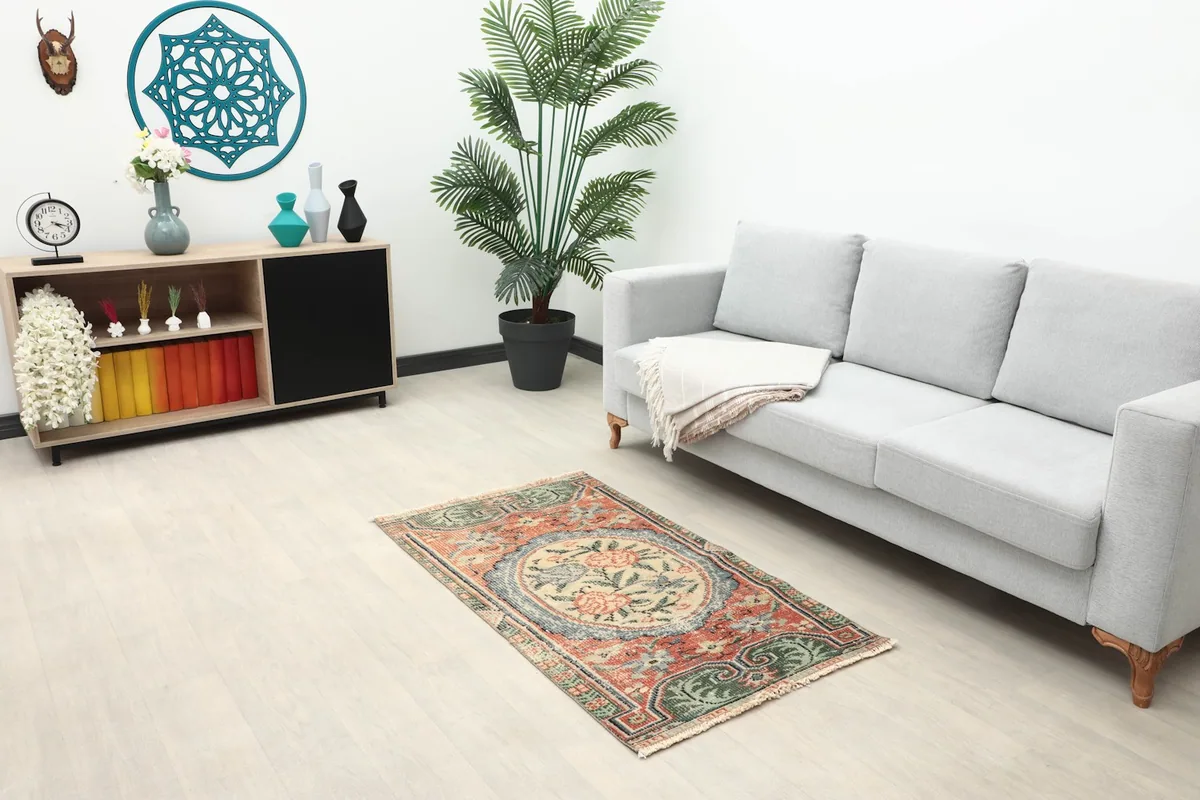 Vintage Anatolian rug displayed in a living room setting with a light gray sofa and wooden cabinet