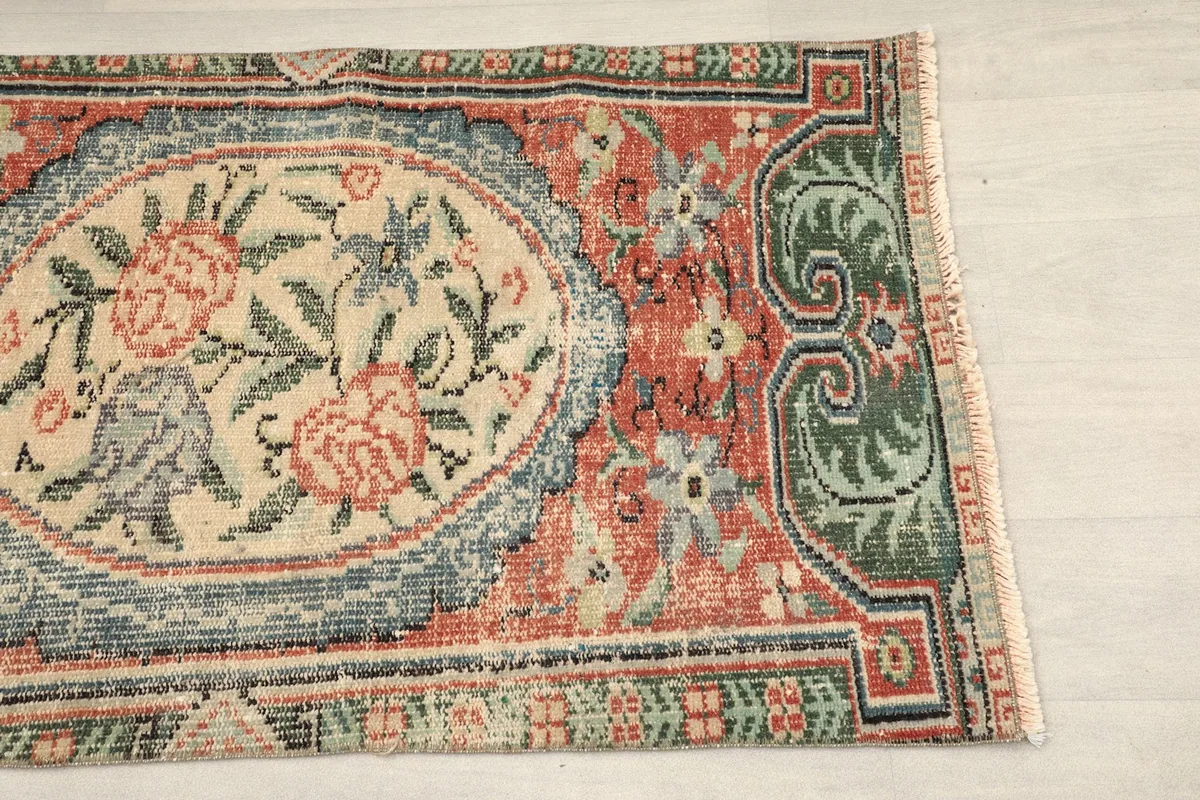 Close-up detail of the rust field and green border of the vintage Anatolian rug