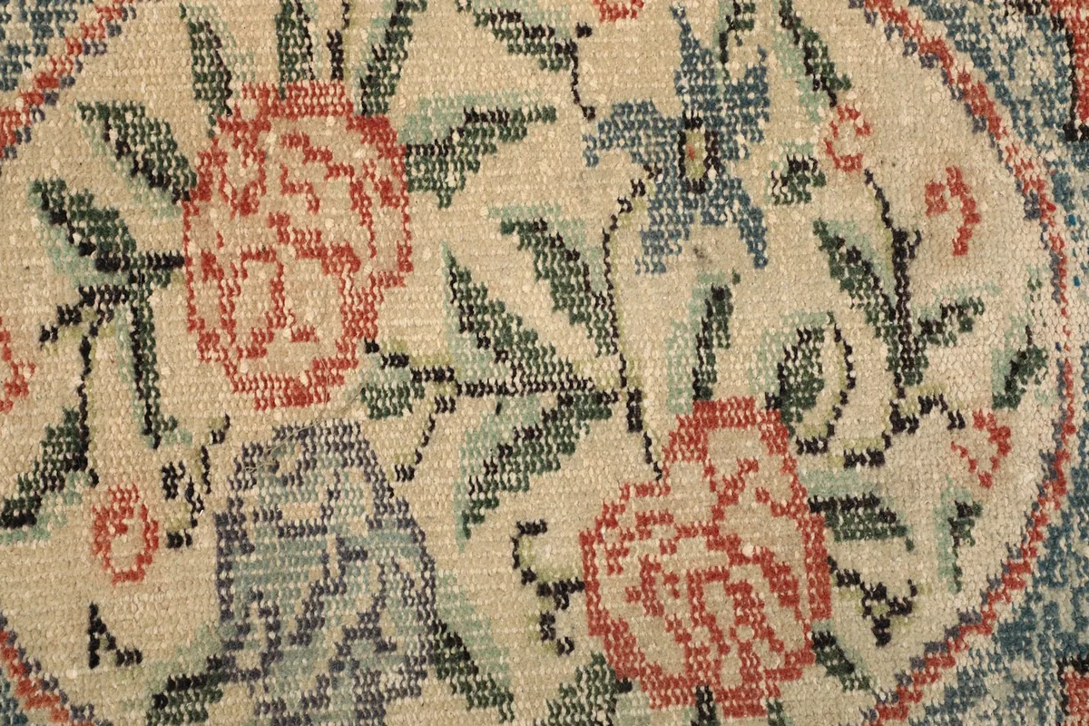 Close-up texture of the low wool pile and intricate floral patterns of the vintage rug